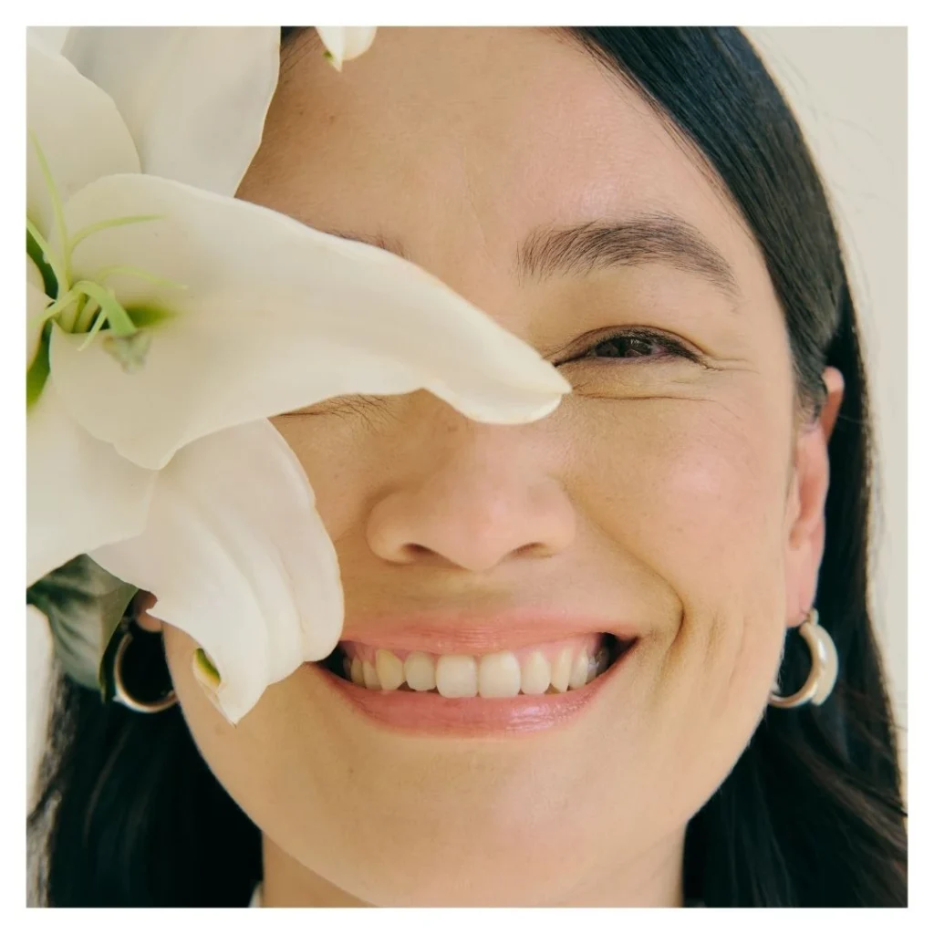 smiling woman with a flower framing her face